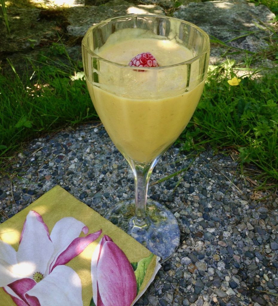 dairy-free mango lassi in glass with raspberry garnish